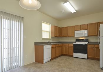 Kitchen with wooden cabinets and white appliances at The Pointe at Manorgreen Townhomes, Baltimore